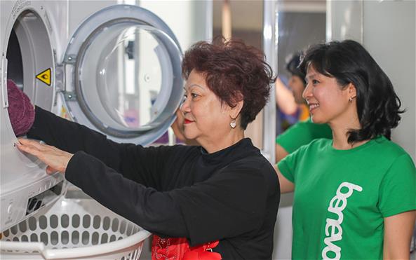 A Benevolent Society staff assisting a client with her laundry duties