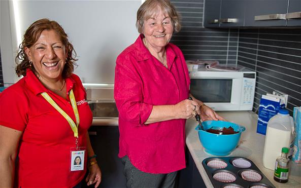 A Benevolent Society staff assisting a senior client with baking cupcakes