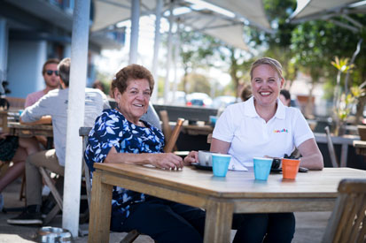 An Aged care client with a tbs worker smiling at a cafe