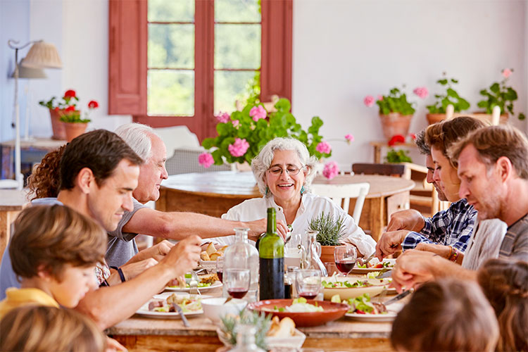 An older woman surrounded by her family eating a meal together at home