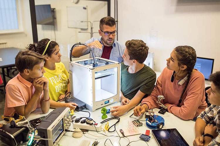 A group of children with their mentor around a 3D printer