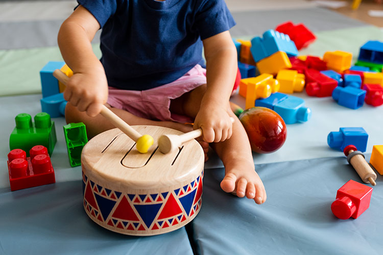 A close up of a young child with a wooden drum