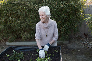 A photo of a senior woman smiling and she does the gardening