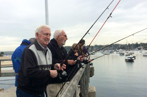 A photo of 2 men fishing off the jetty with fishing rods