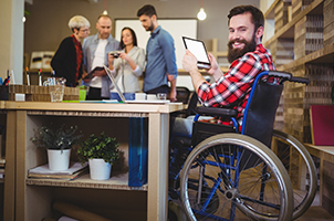 A photo of a man smiling in a wheelchair and using his tablet