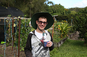 A photo of matthew wearing a hat out in the garden smiling